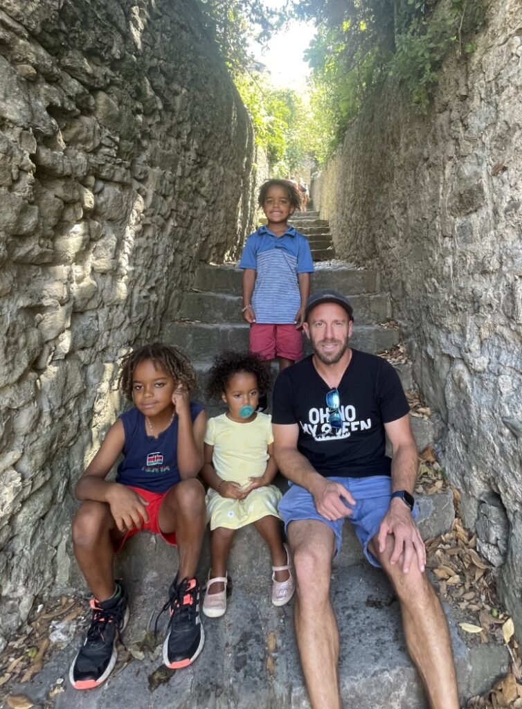 Dr. Michael Greisinger sitting on rocky stairs along with his children